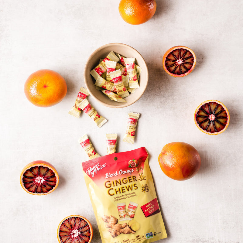 A bowl of Prince of Peace Ginger Candy (Chews) With sliced blood orange on a table.